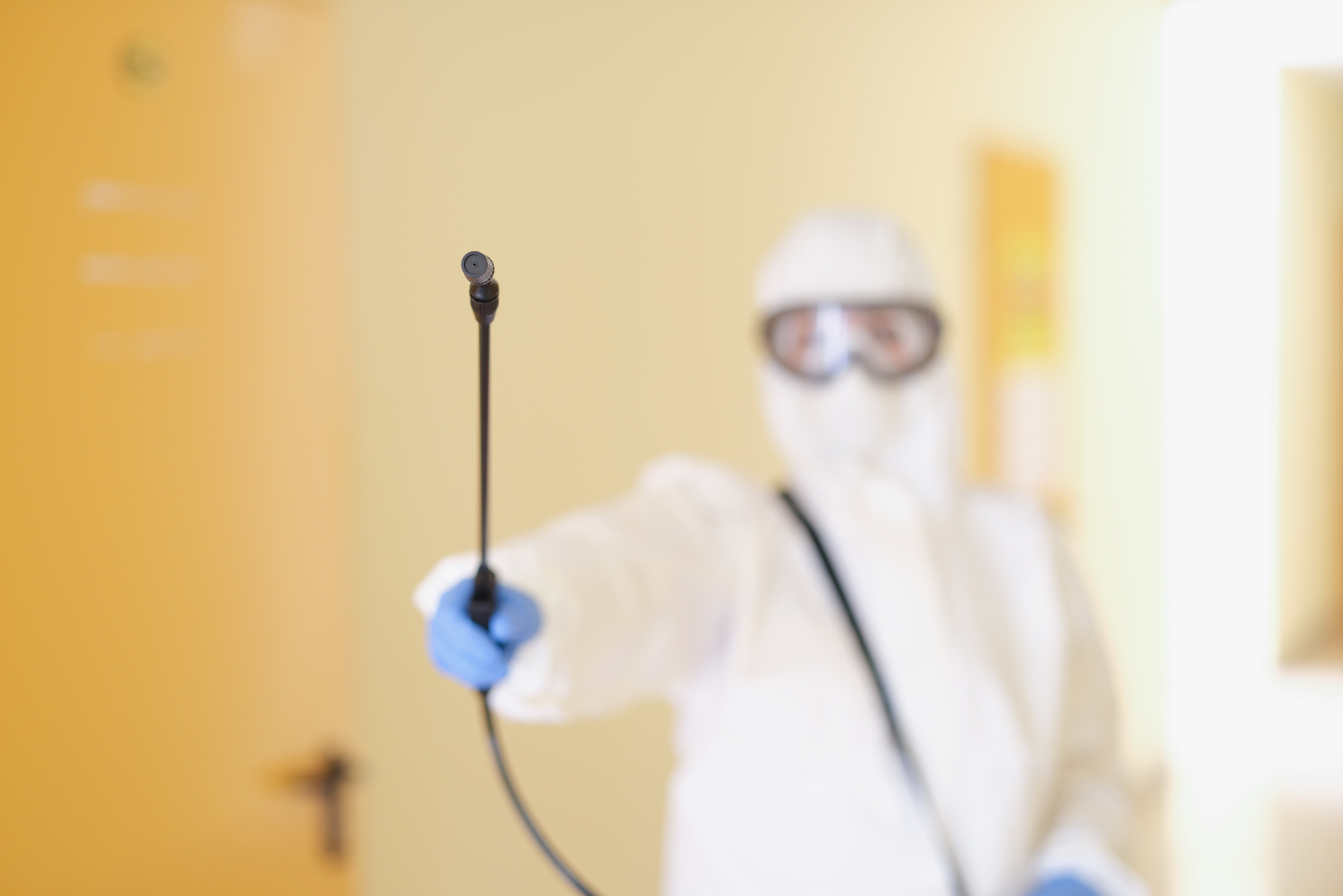 A Man in a Protective Suit Holds a Sprayer, Close-up